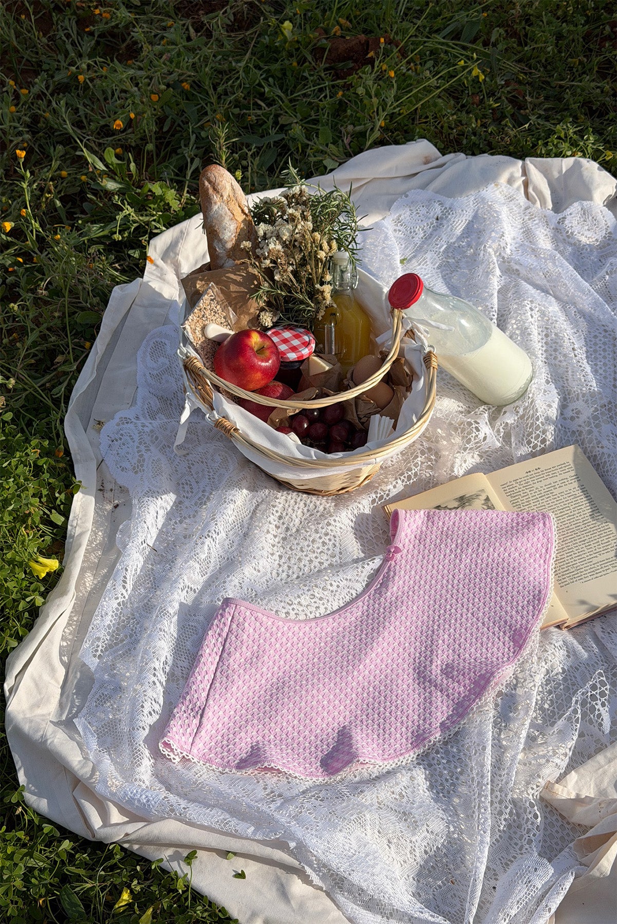 Picnic setup with basket, blanket, and books on grass