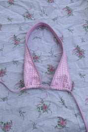 Pink gingham bikini top on a floral fabric background